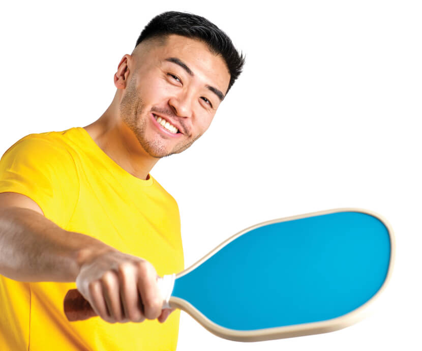Young asian male playing pickleball and wearing bright yellow